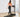 A woman in a pink sports bra and black leggings walks on a treadmill